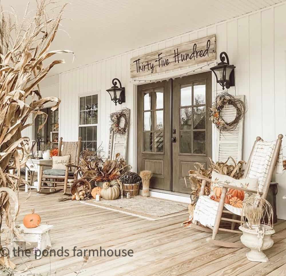 Farmhouse Front Porch with rockers and cornstalks, pumpkins and fall decor.  
