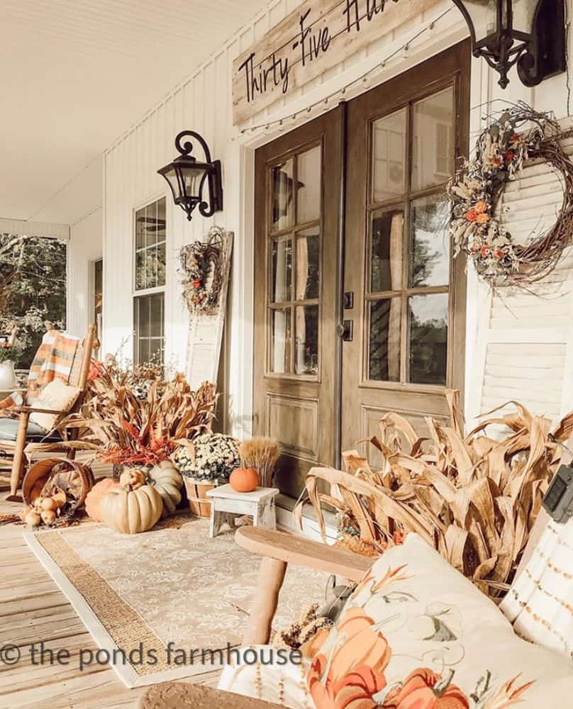 Galvanized tubs filled with cornstalks and shutter surround french doors.  Farmhouse style fall wreaths and pumpkins for fall decorating.  