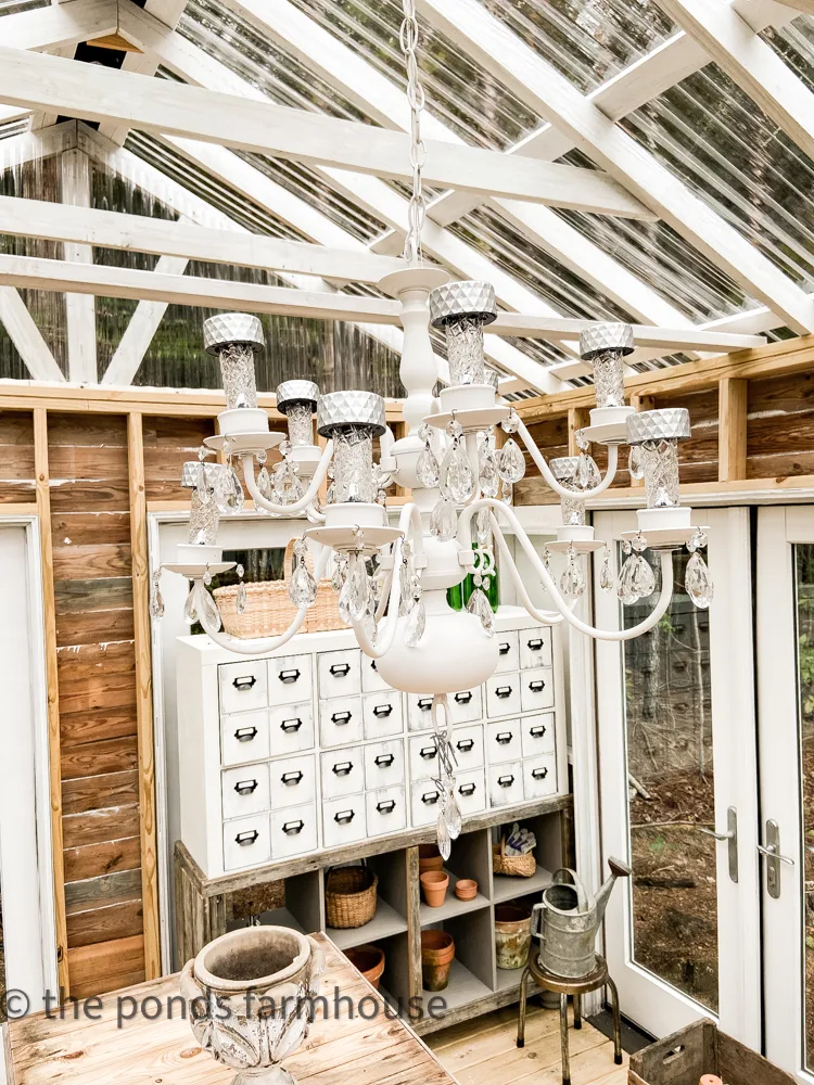 Repurposed Chandelier hold Dollar Tree Solar Lights in Greenhouse