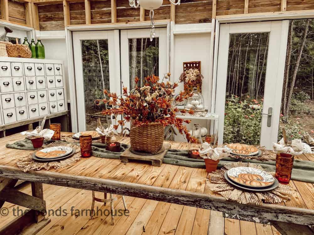 Greenhouse/She-shed with DIY plate chargers and pumpkin plates with a thrifted basket floral centerpiece for fall.