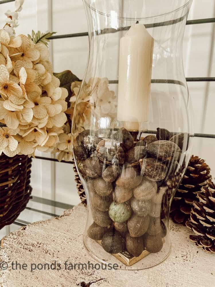 Hurricane glass globe filled with nuts and brass candlestick.