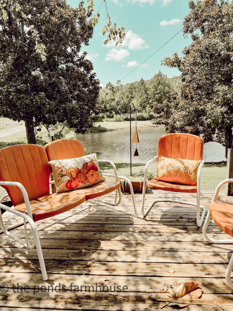 Old Vintage Glider and outdoor metal chairs painted orange and white in front of the ponds.  