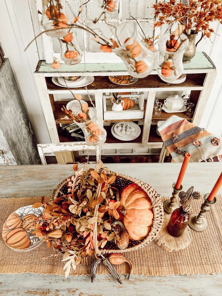 Overhead view of Fall Centerpiece made from baskets, pumpkins and fall flowers.  DIY light fixture filled with mini pumpkins.  