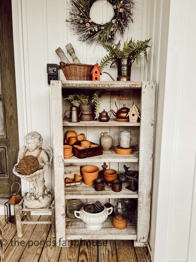 Doorless cabinets found at thrift store holds thrifted garden items, terra cotta clay pots, birdhouses, vintage copper.  