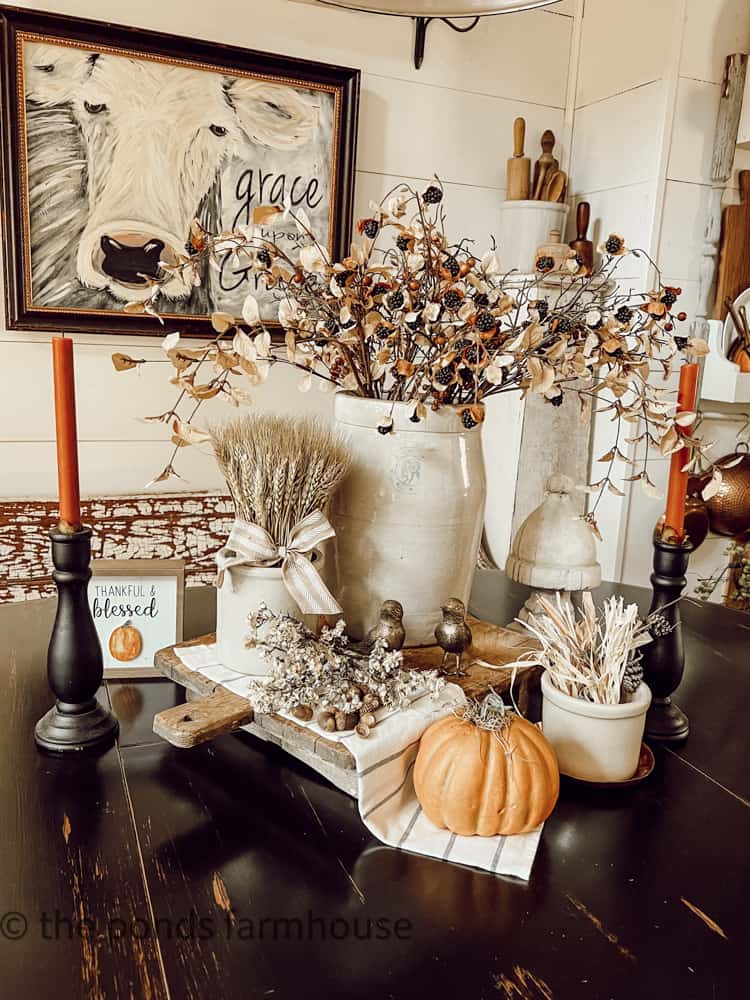 Fall centerpiece ideas with thrifted decor such as old crocks, candlesticks, and autumn florals.