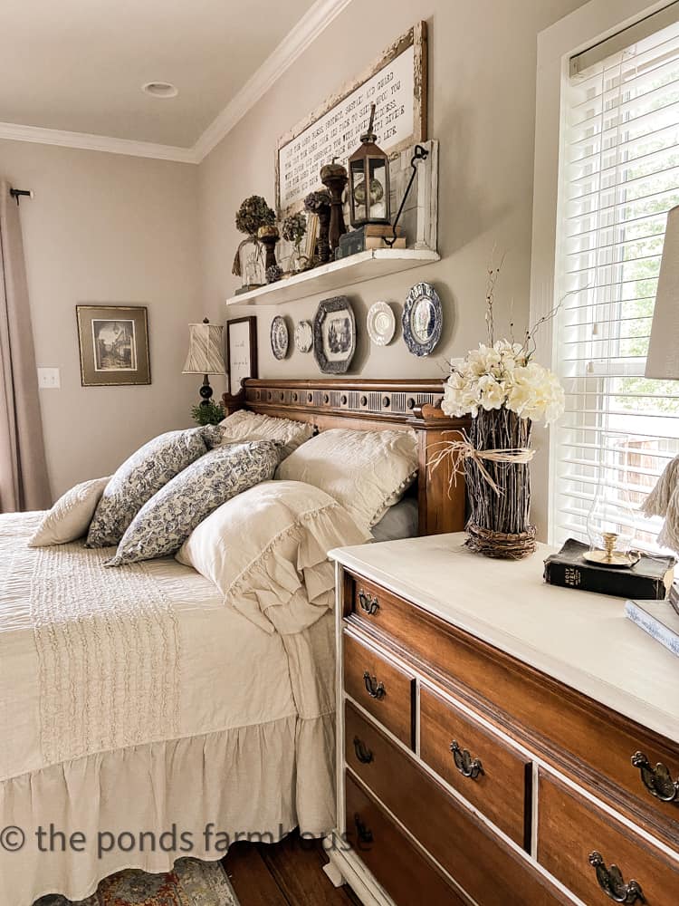 Twig vase with hydrangea flower arrangement on side table in bedroom.