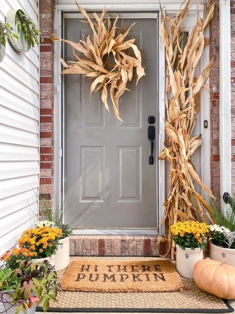 Small porch decor for fall with mums, corn stalks and diy corn husk wreath. 
