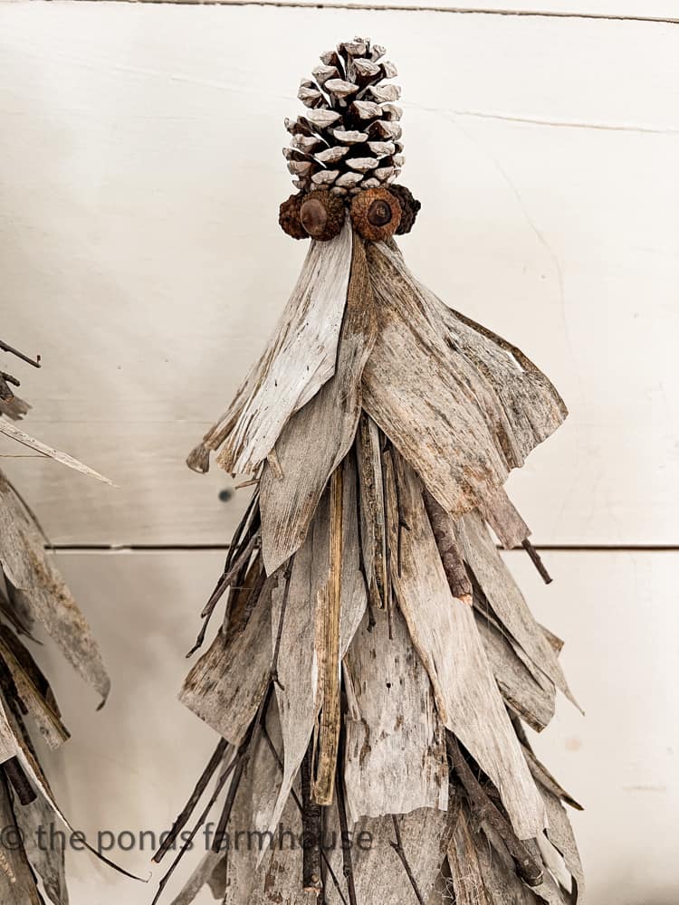 Pinecone and acorns adorn the top of the DIY craft project using corn stalks for making fall decor. 