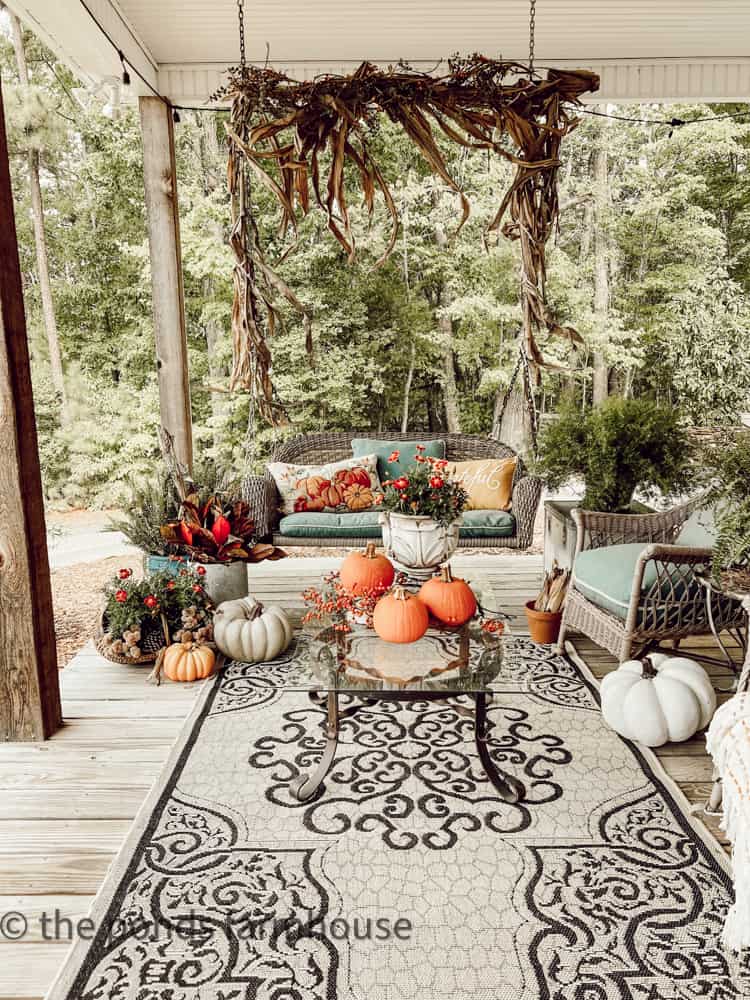 Seating area with porch swing and vintage wicker, diy coffee table and large rug.  