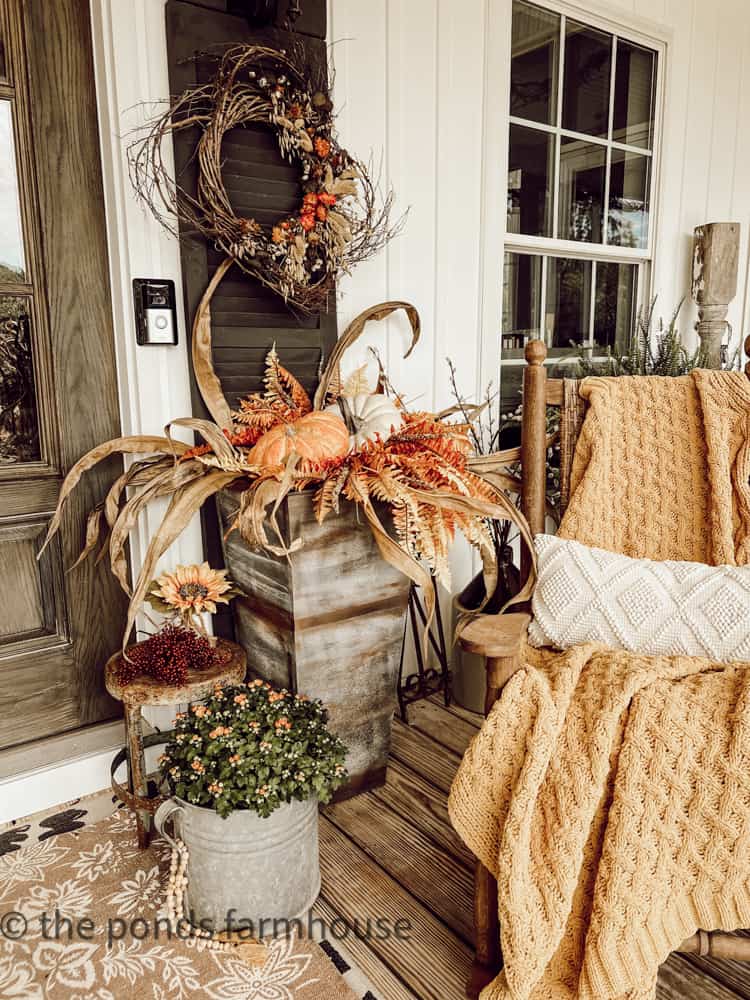 Planters filled with pumpkins and corn stalks for cozy front porch