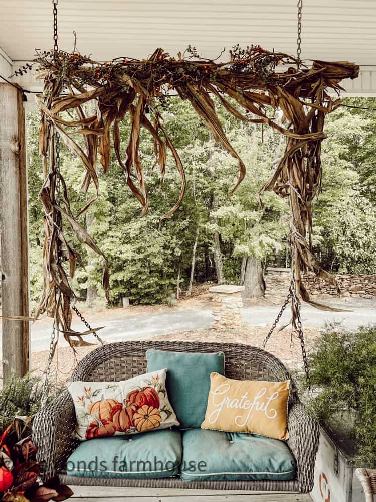 porch swing with corn stalk garland and fall throw pillows