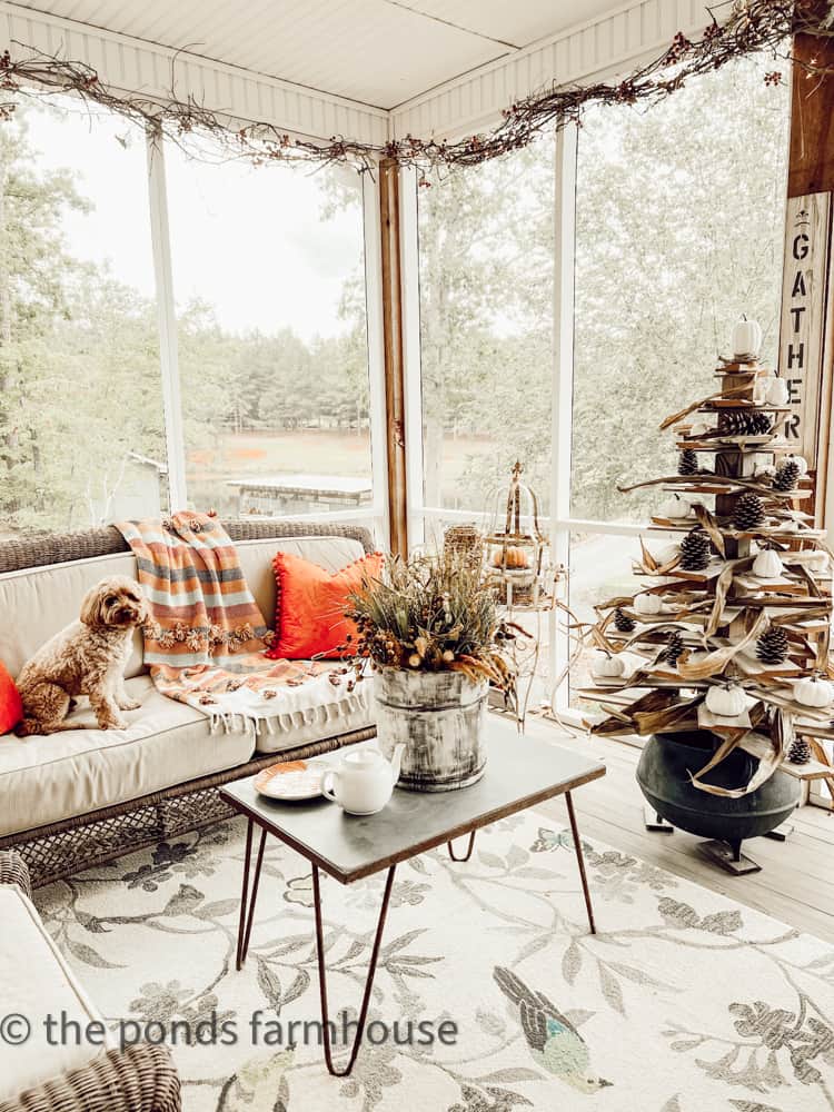 Farmhouse Screened-in Porch Decorating for Fall.  Burnt Orange Pillows and Colorful Throw Blanket