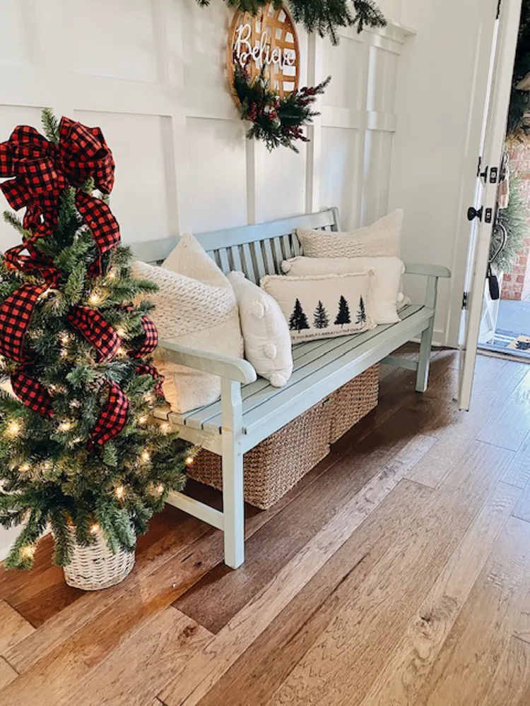 Entryway decorated for Christmas with Christmas Tree and bench filled with cozy pillows