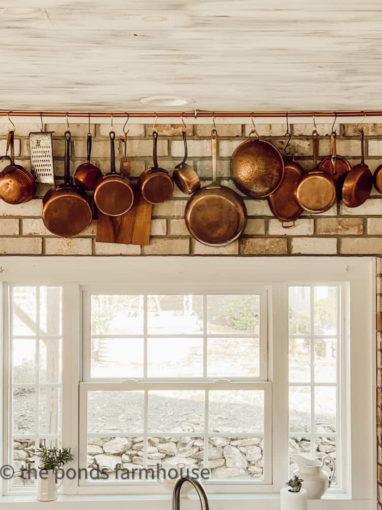 https://www.thepondsfarmhouse.com/wp-content/uploads/2022/10/Close-up-DIY-Copper-Pot-Hanging-Rack-copper-pots-on-brick-wall-in-kitchen.jpg