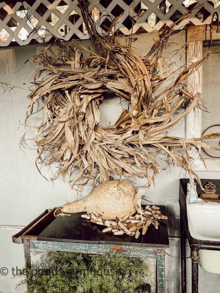 DIY Corn Husk Wreath combined with a dried gourd by the outdoor kitchen sink. 