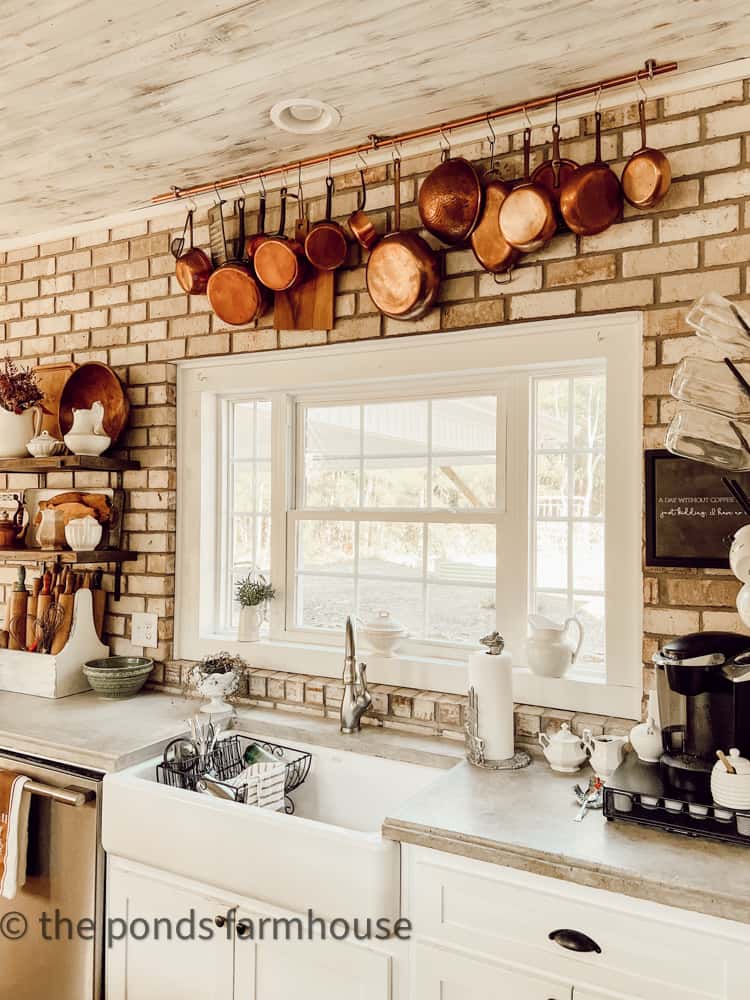 DIY Farmhouse Kitchen concrete countertops and farm sink with brick wall and copper hanging pots. 