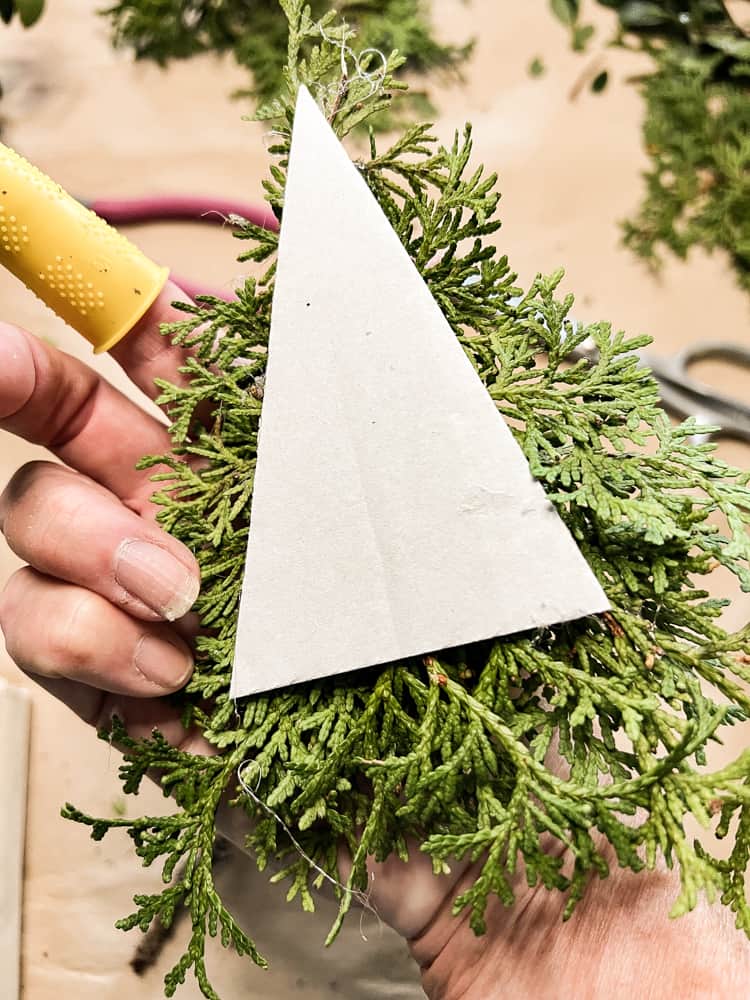 Add cedar greenery for Christmas to tree-shaped cardboard for DIY holiday decorations.