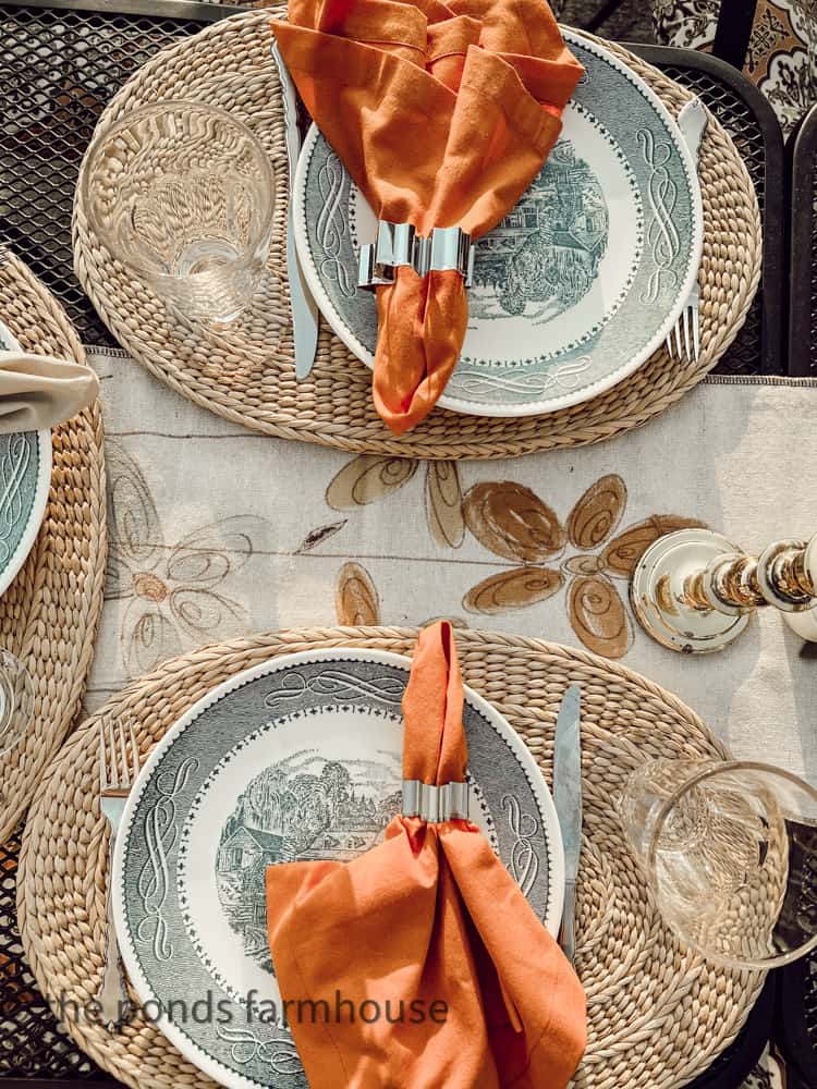 Hand painted table runner made from a drop cloth fabric and vintage dishes set the outdoor kitchen table.  