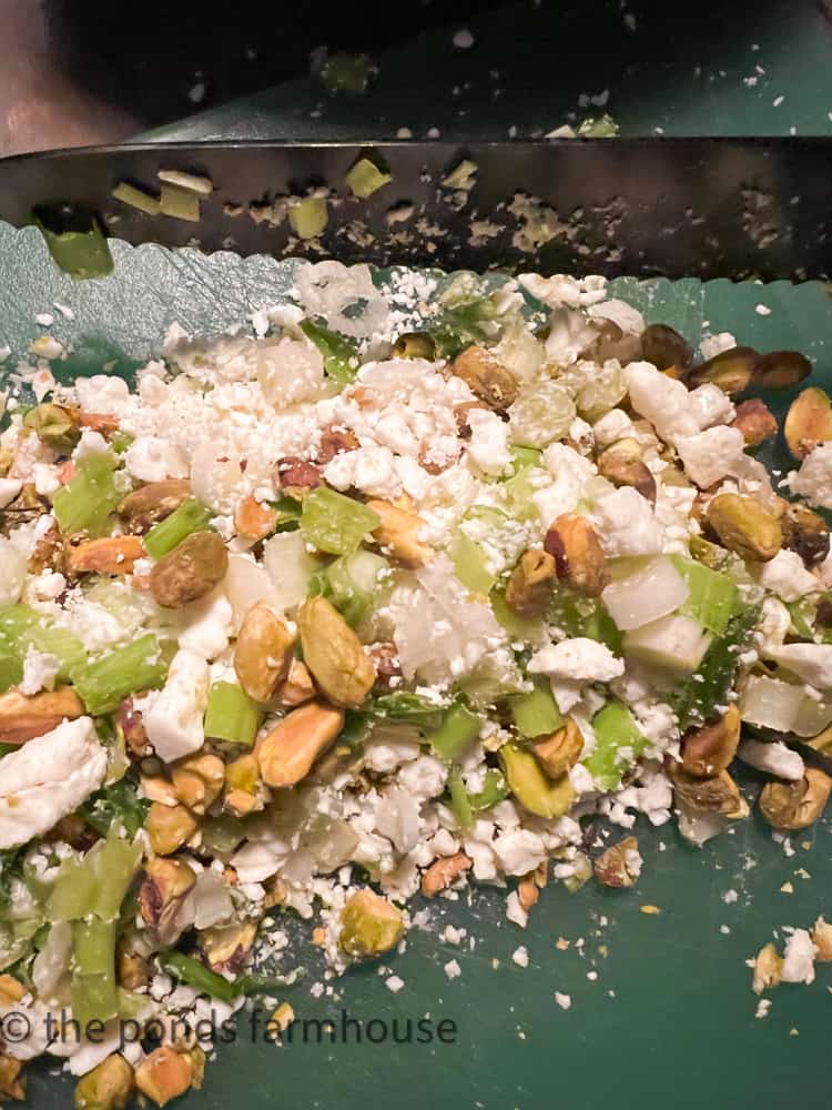 Chop Green onions, feta cheese, pistachio nuts on chopping board for pistachio recipe.