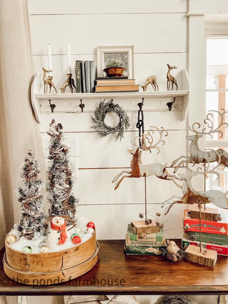 Entry table with shelf and vintage brass reindeers, vintage sifter, shiny brite boxes and metal reindeer