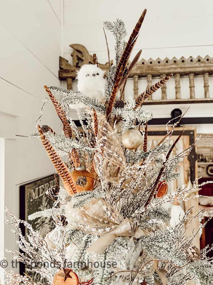 Pheasant Feather and frosted stems mix with ribbons for cheap ways to decorate Christmas trees in 2023.