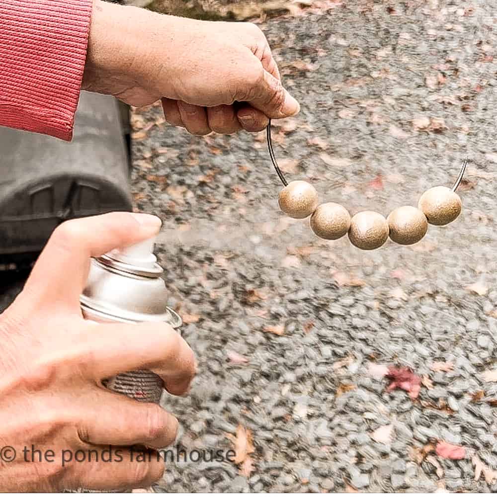 Spray paint wooden beads with gold paint.