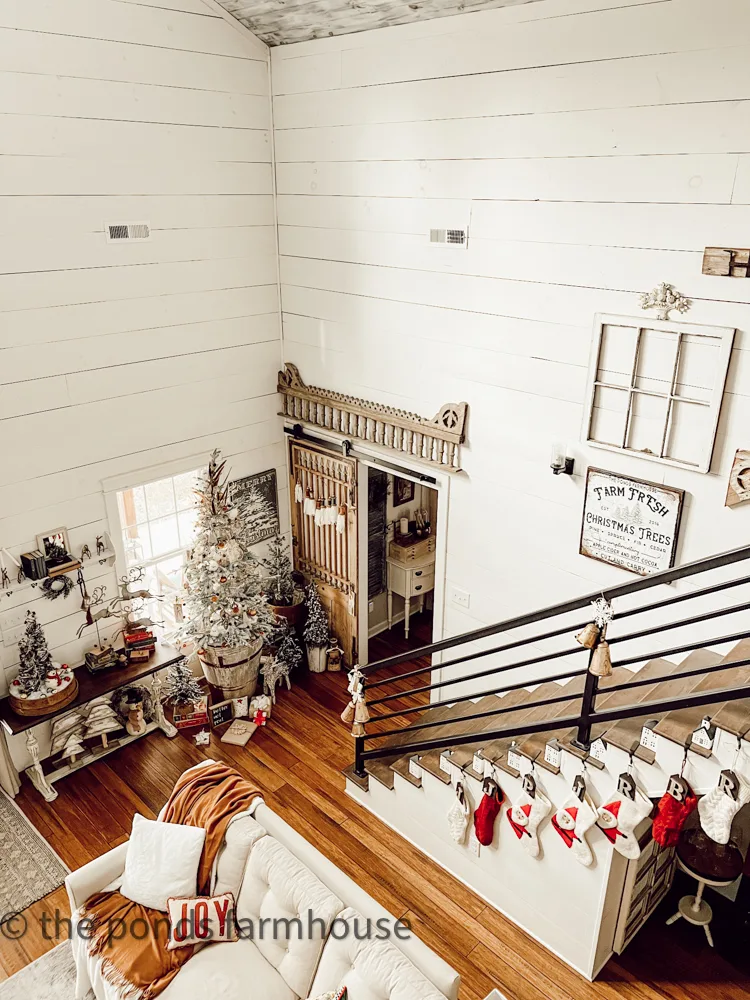 Loft view of industrial-style staircase and Christmas Tree beside barn door. Salvaged Architectural  elements decorate the gallery wall