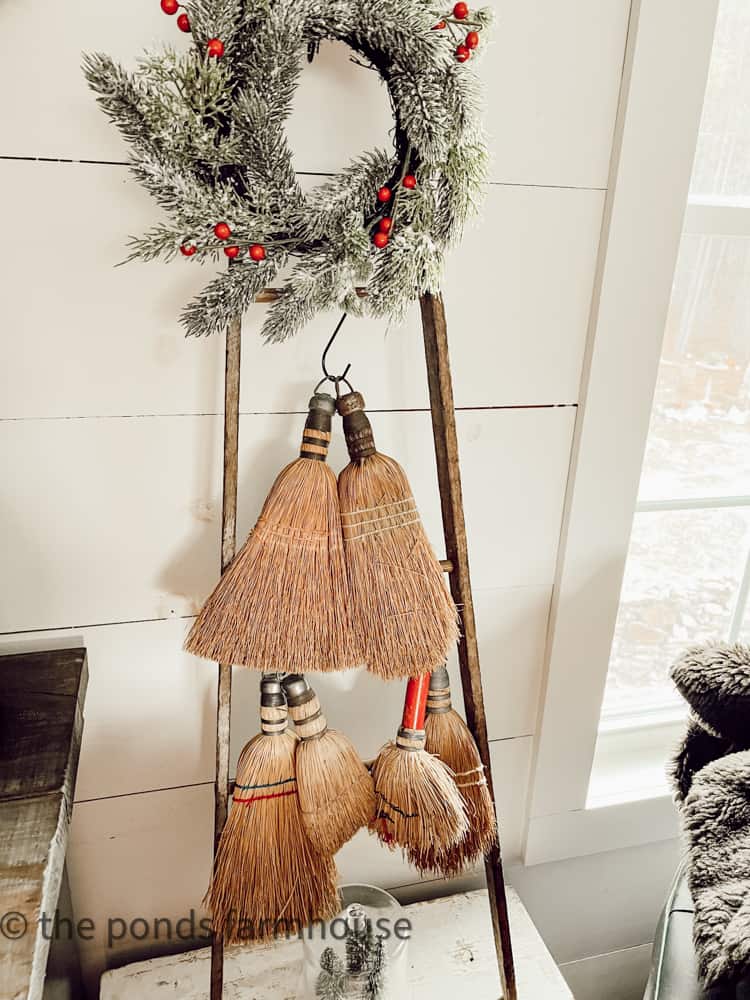 Tobacco Stick ladder holds vintage brooms and small Christmas Wreath