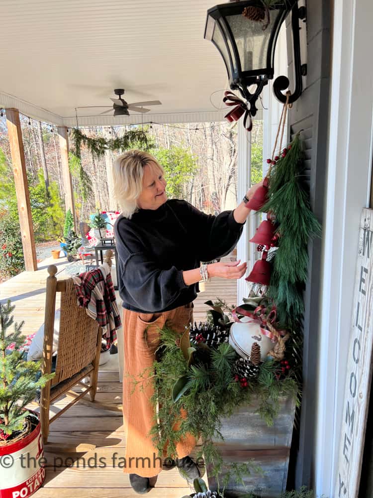 Decorating the front porch DIY Shutters with pine swag and red bells.