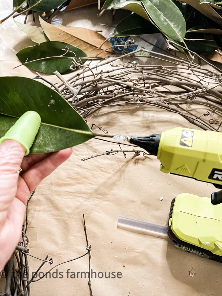 Add hot glue to magnolia leaves to attach to grapevine wreath.