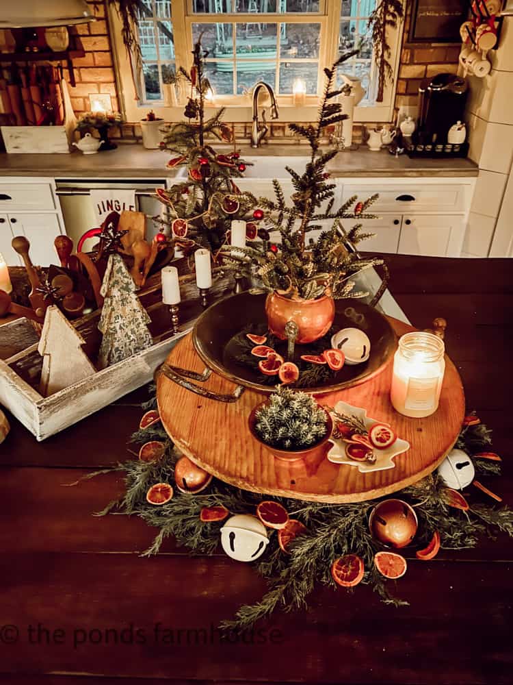 Modern farmhouse with kitchen island filled with french cheese board and vintage antique copper, dried oranges and repurposed bells
