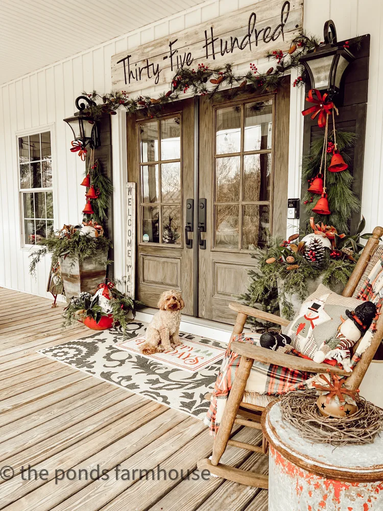 French Doors on Farmhouse Porch Decorated for Christmas with Rudy, mini goldendoodle sitting on rug