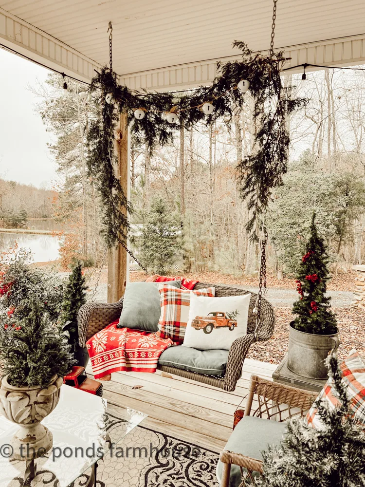 Front Porch Swing with real Cedar Garland and white jingle bells, cozy pillows and warm throw blanket