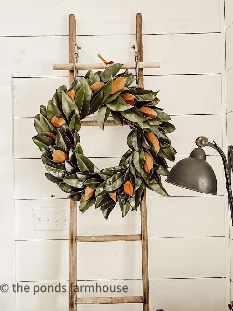 DIY Spring wreath with fresh magnolia leaves hanging on a vintage ladder.  Farmhouse Springtime wreath.