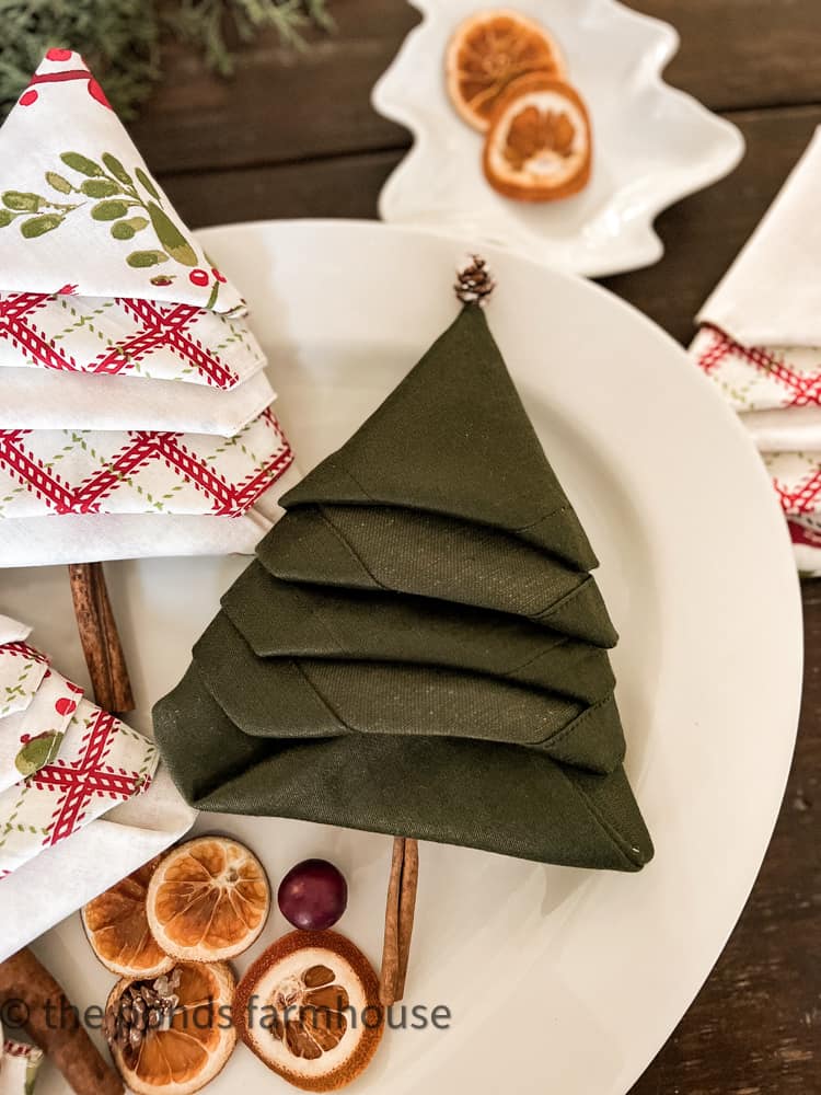 Green Christmas Tree Shaped Napkin with cinnamon stick and pinecone garnish.