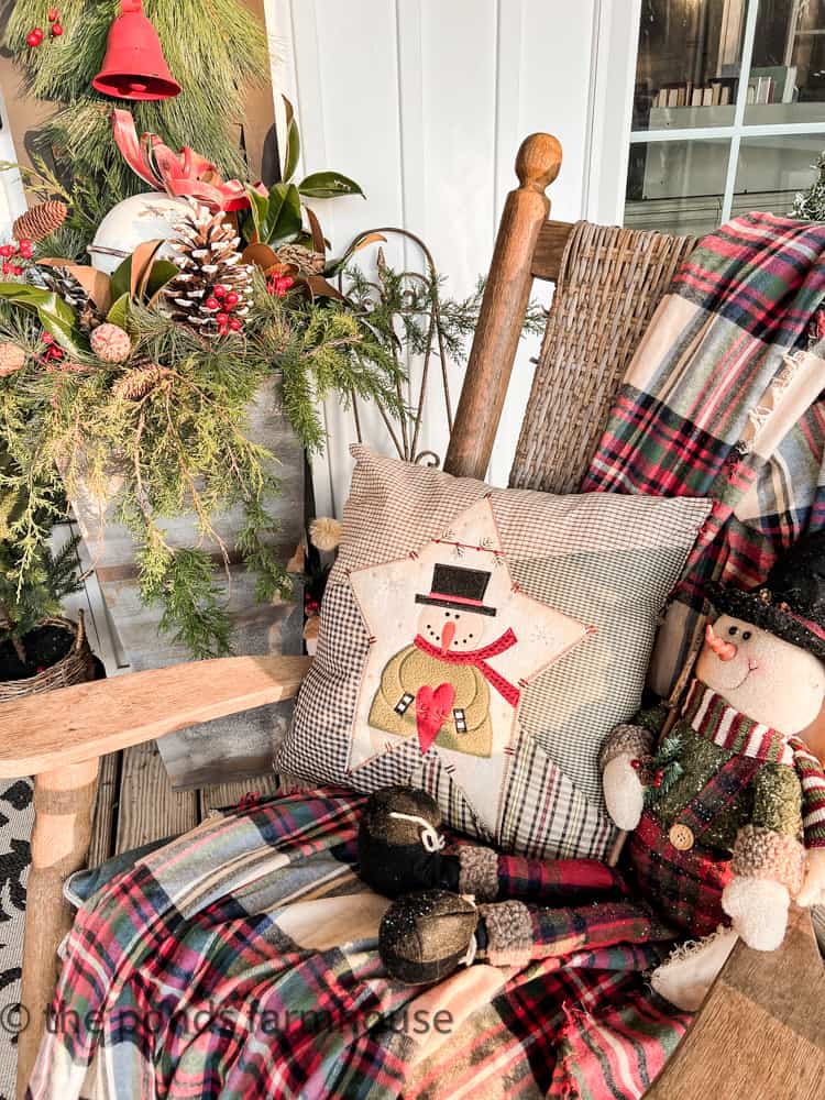 Cozy throw blankets, a snowman and snowman pillow fill the Kennedy Rocking Chair on front porch.