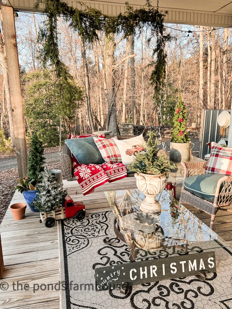 Farmhouse FRont Porch Swing and antique wicker chairs.  Glass top coffee table decorated for Christmas
