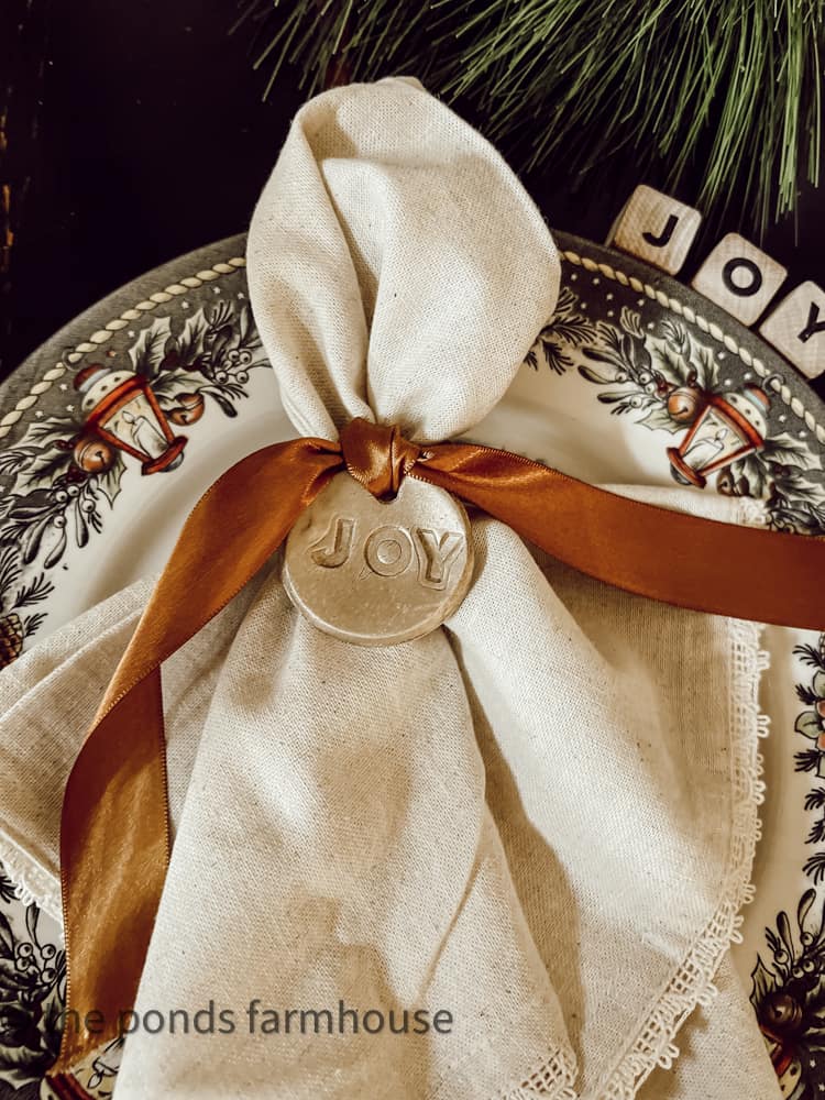 Air Dry Clay Ornament used as a napkin charm tied with copper ribbon around a linen napkin.