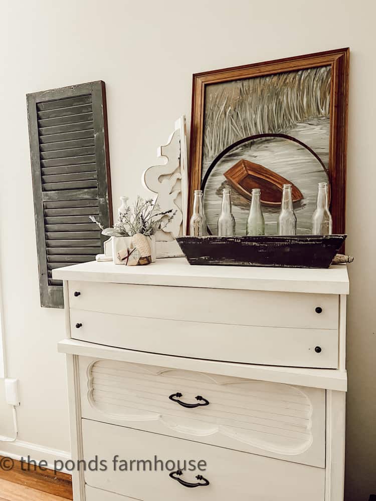 Thrift Store Chest of Drawers with boat painting and vintage soda bottles decorate guest bedroom.