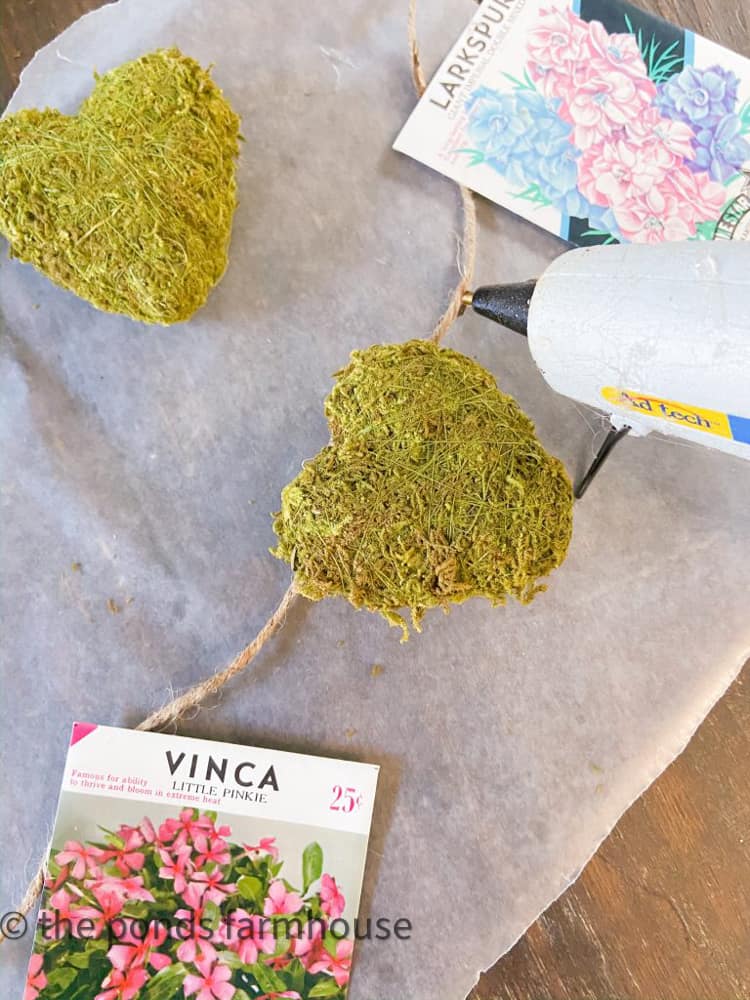 Use hot glue to attach vintage seed packets to jute twine for DIY Spring Garland.