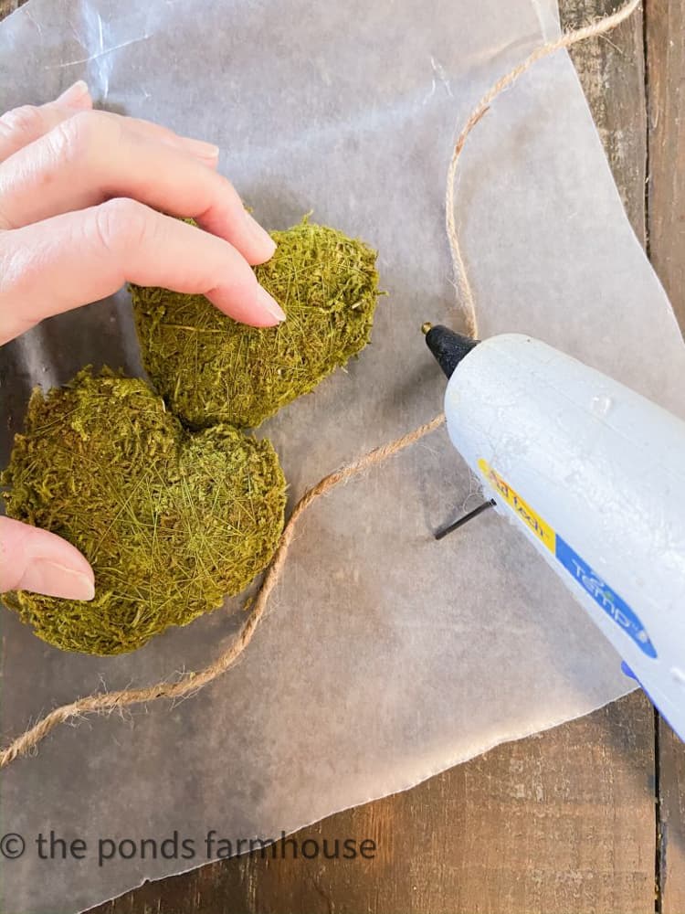 Use hot glue to attach moss hearts to jute twine for a Spring Garland