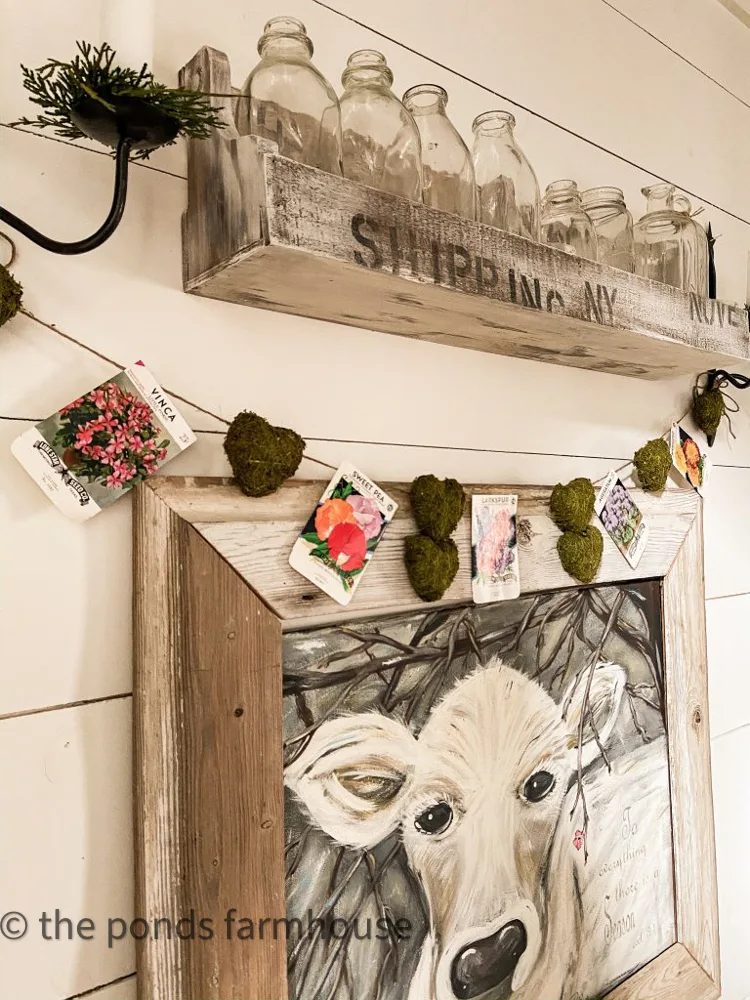 Vintage Seed Packet and moss heart garland over Faith Cow Painting.