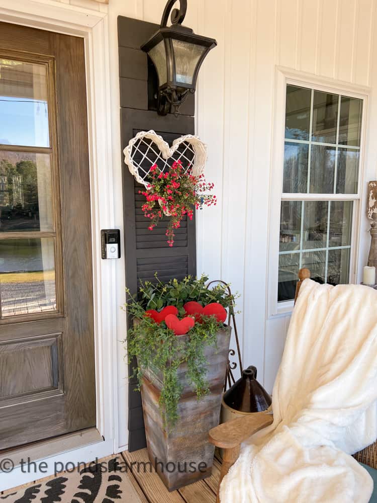 DIY planter filled with wooden red heart trio and faux greenery with thrifted white heart basket on shutter