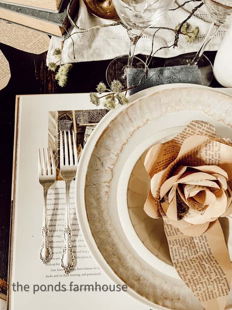 Vintage silverware and paper roses on coffee table book. 