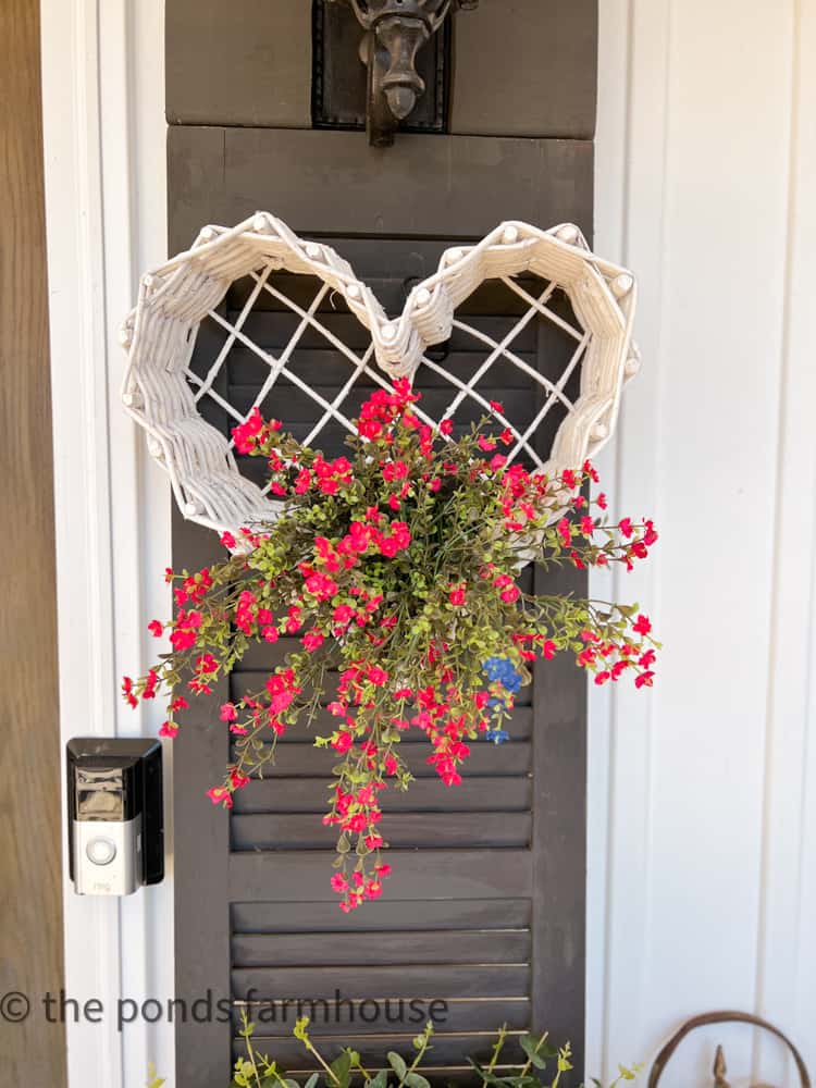 thrift Store White Heart Basket on a black shutter and faux flowers for Valentine's Door Decorations