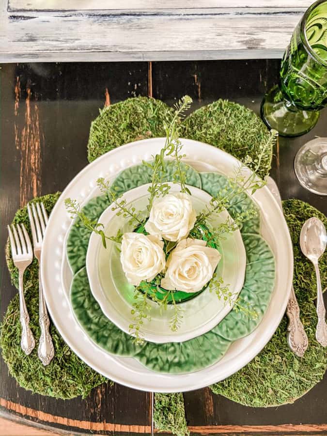 White roses in vintage green bud vase on green and white dishes with shamrock placemat.