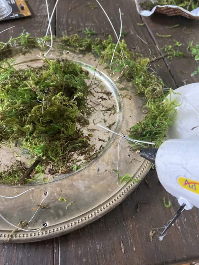 Use hot glue to attach moss to the plate chargers to make twig plate chargers.