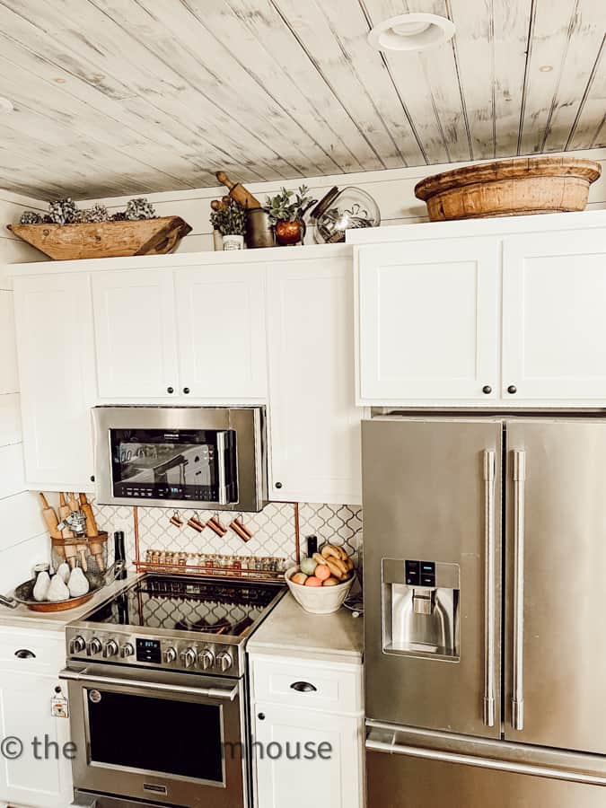 Decorate above kitchen cabinets with vintage dough bowl and larger wooden bowl, old rolling pins and crocks