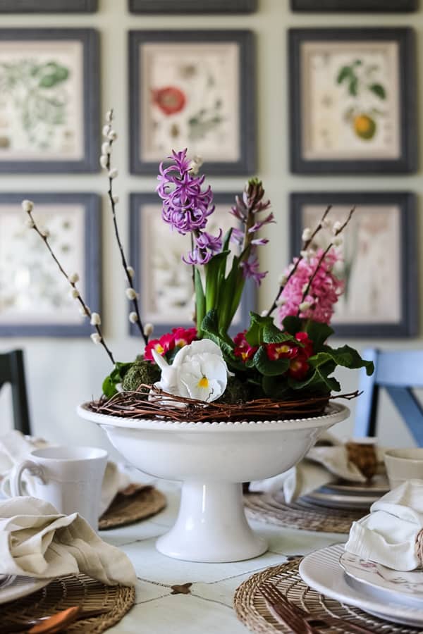 Easter Home Decor Ideas. Beautiful floral centerpiece with milk glass container and grapevine wreath for Easter Tablescape - 16 Easter Ideas