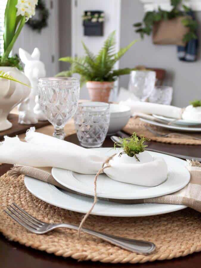 White Napkin with cracked egg and green preserved moss in the egg for Easter Table setting.